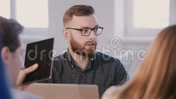 中镜头年轻的职业白种人商人在头脑风暴小组会议上与同事交谈视频的预览图