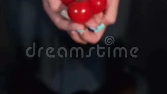 红色的西红柿在女人手中水滴在黑色的背景上视频的预览图