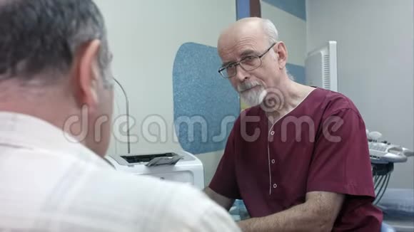 成熟的医生在他的办公桌前做一些笔记听一个资深的病人视频的预览图