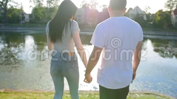 浪漫的夫妇去池塘在公园的绿草上坐下来后景夫妻信任爱情和幸福视频的预览图