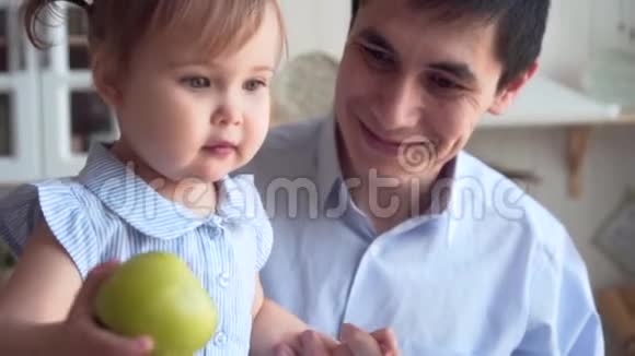爸爸和女儿在厨房里爸爸抱着女儿女儿把一个绿色的苹果扔在地板上视频的预览图