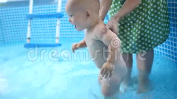 一岁的孩子在母亲的监护下在充气游泳池里洗澡孩子拍手妈妈夏天夏天视频的预览图