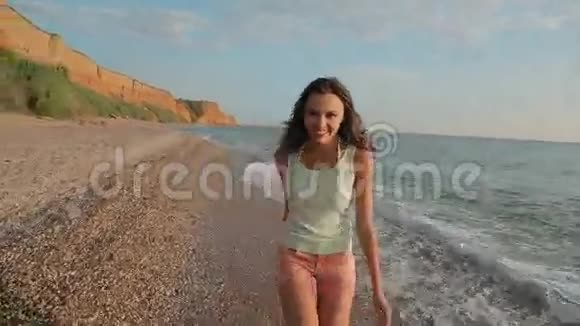 快乐的女孩光着脚在海滩上奔跑视频的预览图