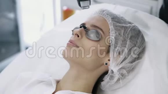 特写美容医生用特殊设备对女性面部进行激光血管切除视频的预览图