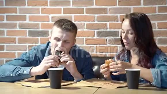 在咖啡馆或家里吃汉堡包的快乐夫妇视频的预览图