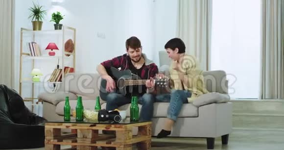 一对夫妇在家里和他们的朋友在客厅里举行聚会他们用吉他滑稽的舞蹈和感觉唱歌视频的预览图