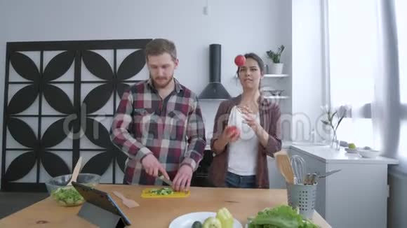有趣的烹饪快乐的女性与男性跳舞并在晚餐烹饪蔬菜沙拉的乐趣以健康视频的预览图