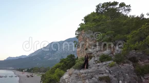 在海边的岩石悬崖上鸟瞰年轻女子视频的预览图