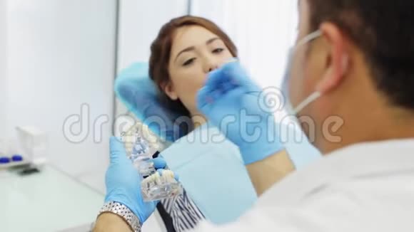 牙医解释了手中拿着珠宝模型的牙科修复术的过程视频的预览图