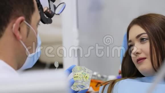 在咨询过程中女士正在看正畸医生拿着带牙套的下巴模型视频的预览图