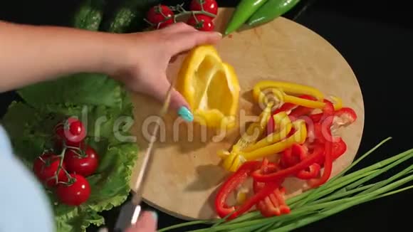 一个女人在木板上切成熟多汁的黄椒的特写镜头视频的预览图