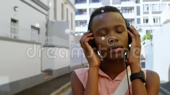 美丽的非洲裔美国人听音乐带耳机在城市街头视频的预览图