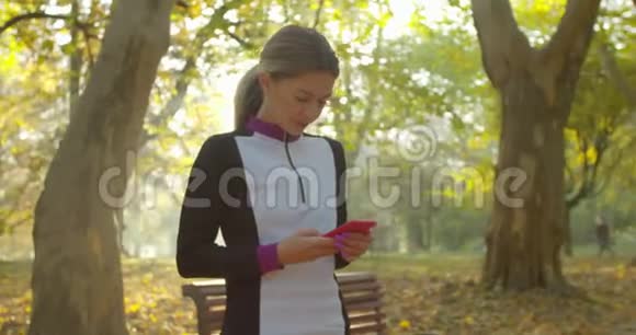 城市公园背景下年轻女性跑步和使用智能手机后的肖像视频的预览图