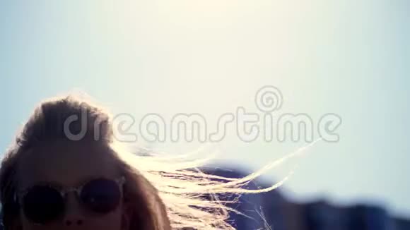 肖像戴太阳镜的青少年女孩在阳光下跳舞她的头发在风中飘扬视频的预览图