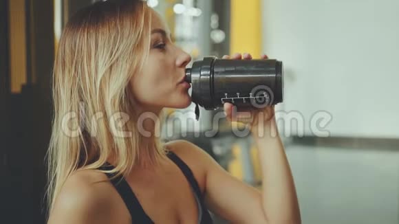 有魅力的年轻运动女孩在专业健身房喝水视频的预览图