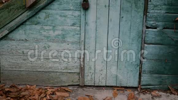 废弃的毁坏的旧木屋楼梯和门用风化油漆剥落的枯叶特写镜头视频的预览图