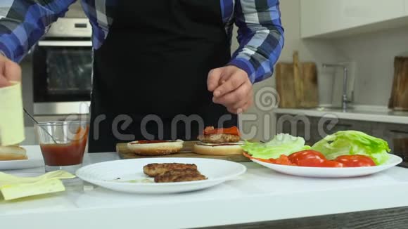 一个丰满的男人在他的厨房里在家里做汉堡包那家伙把奶酪放进汉堡包里不健康的生活方式油炸视频的预览图