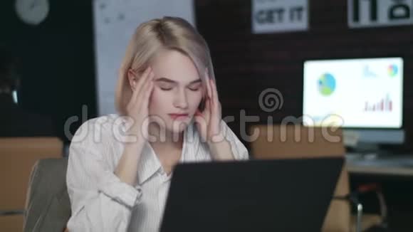 工作过度的女人在夜间办公室头痛有压力的女人工作到很晚视频的预览图