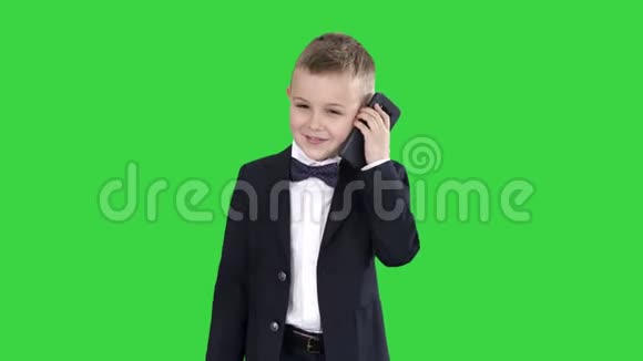 穿着服装的小男孩在绿色屏幕上行走时打电话Chroma键视频的预览图