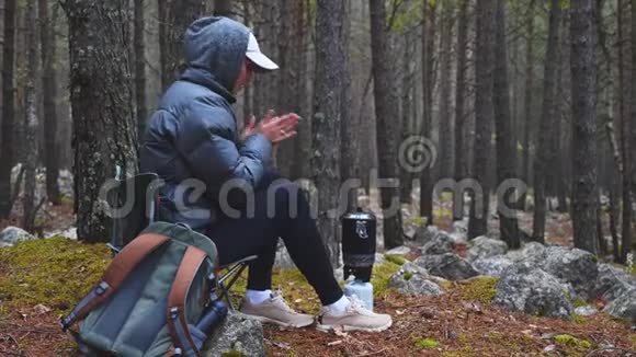 女人在森林里打开煤气燃烧器用温水煮茶用火加热视频的预览图