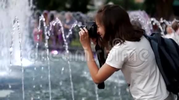 美丽的女摄影师在喷泉附近有一个专业的室外摄像机视频的预览图