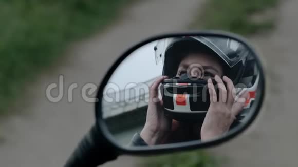 红发少女从头上摘下头盔透过摩托车的镜子反射慢动作视频的预览图