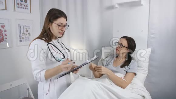 在医院里友好的女医生检查躺在床上的生病的女病人他报告了他的投诉他们视频的预览图