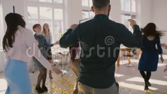 镜头围绕年轻的多民族商业集团庆祝成功跳舞在有趣的工作场所聚会慢动作视频的预览图