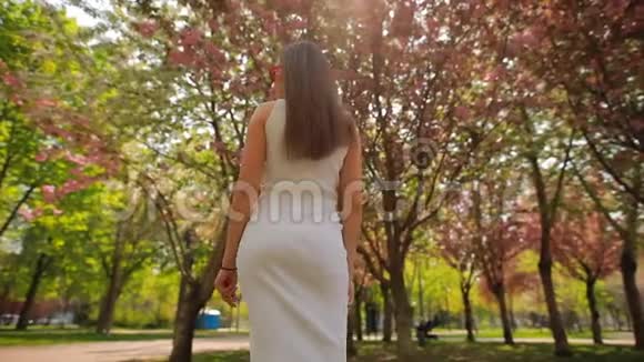 夏季公园观花树摸头发的女性后景视频的预览图