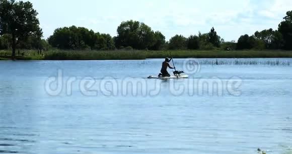 一只狗和它的主人一起漂浮在湖上的木板上视频的预览图