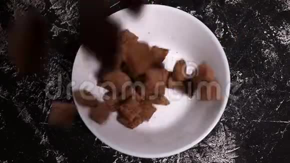 巧克力片的特写垫子掉在黑色背景上的白色盘子里谷物食物厨房概念视频的预览图