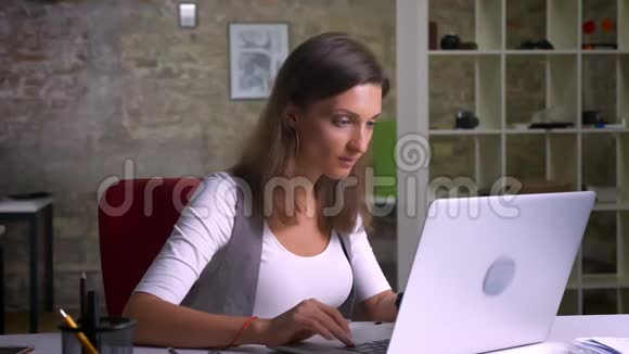 漂亮的女办公室工作人员坐在笔记本电脑前对好消息感到兴奋手忙脚乱视频的预览图