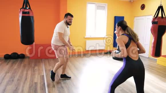 健身俱乐部拳击教练个人培训一个强壮的男人和一个苗条的女孩开始打架练习与练习视频的预览图