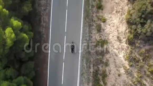 摩托车手驾驶他的摩托车在乡间的山路上空中观景视频的预览图