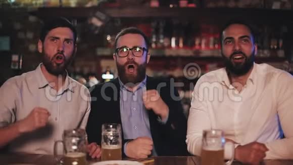 三个老朋友喝啤酒在酒吧一起欢呼足球迷友谊运动理念视频的预览图