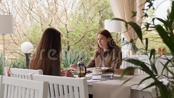 午餐慢动作咖啡厅两个时髦女孩交谈的侧视图视频的预览图