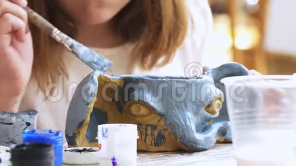 小女孩用蓝色的颜色她的手工大象杯从粘土在艺术车间视频的预览图