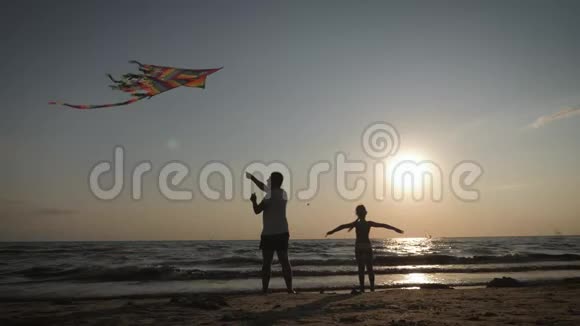 幸福的家庭父亲和孩子女儿在日落时在海滩上放风筝有趣的家庭时光友好家庭的概念视频的预览图