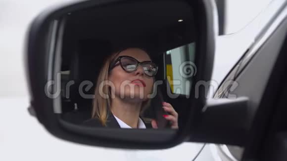一位戴眼镜的美女坐在汽车经销商的车里一边打电话视频的预览图
