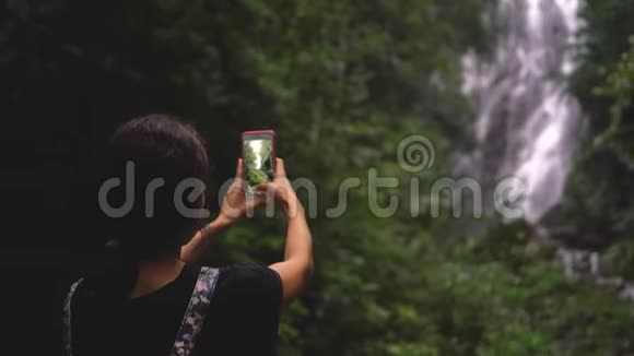 一个女人正在给瀑布拍照视频的预览图
