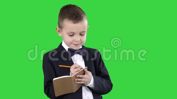 男孩穿着正式的衣服写在支票单或笔记本上的绿色屏幕色度键视频的预览图