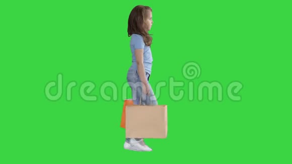 活泼开朗的女孩带着购物袋走在绿色屏幕上Chroma键视频的预览图