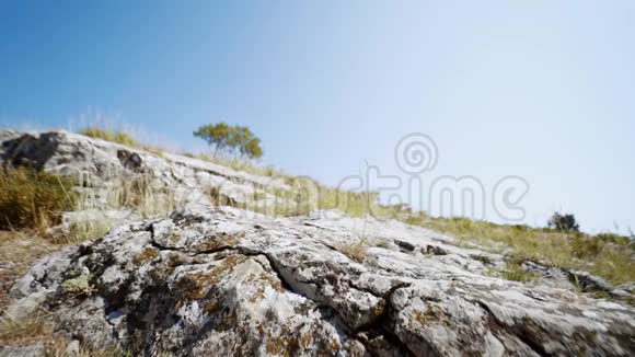 夏日迎着蓝天漫步在岩石坡上的年轻成年徒步旅行者视频的预览图