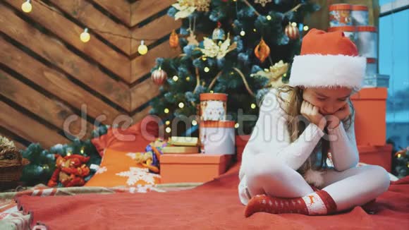 失望的小女孩穿着圣诞服装坐在洛托斯的位置上在木制的圣诞背景下皱眉视频的预览图