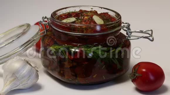 女人关上一罐干番茄用西红柿在罐子里一支迷迭香大蒜和香料涂上橄榄油视频的预览图