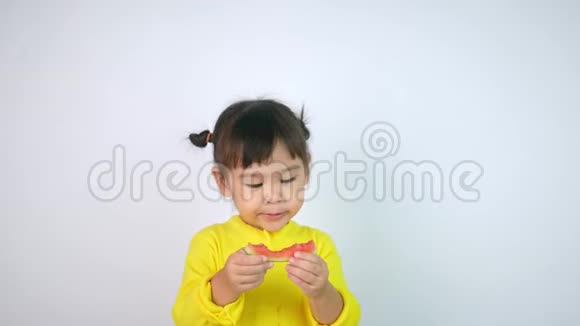 一个快乐微笑的亚洲儿童女孩的肖像享受吃西瓜孤立在白色背景视频的预览图