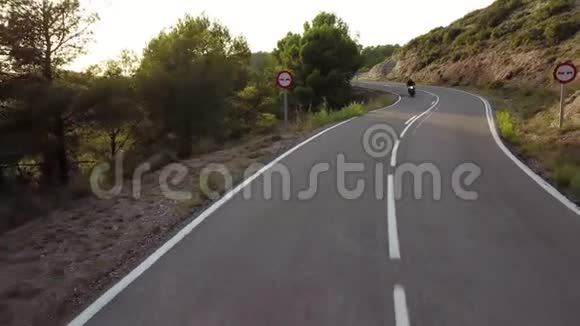 摩托车手驾驶他的摩托车在乡间的山路上空中观景视频的预览图