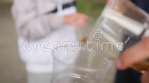 把柠檬水从瓶子里倒入塑料玻璃里伙计们喝柠檬水近距离射击视频的预览图