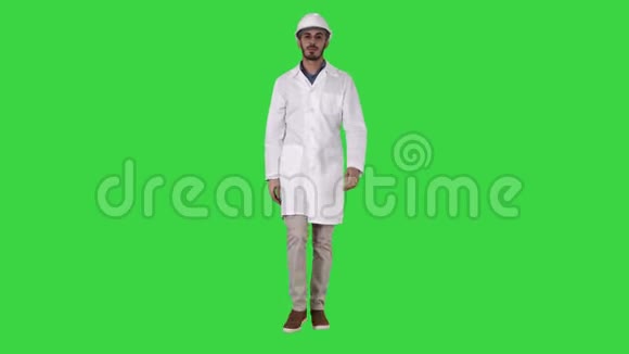 戴着头盔和白色长袍的阿拉伯工程师在绿色屏幕上向前走Chroma键视频的预览图