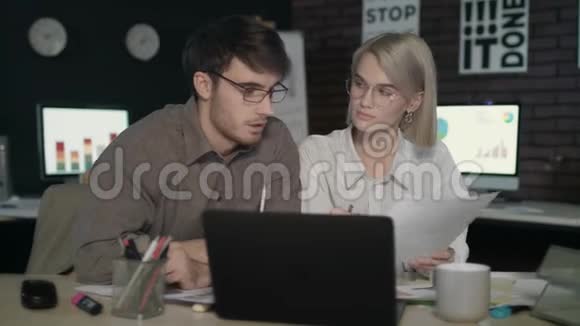商务夫妇在黑暗的办公室里看着财务报告前台电脑视频的预览图